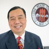 Donaldo Fong standing in front of FSU Seal