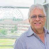 Adolfo Leyva standing in front of FSU seal