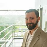 Adam Tratner standing in fromt of FSU logo