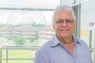 Adolfo Leyva standing in front of FSU seal