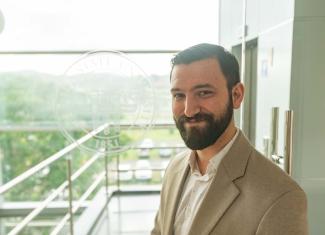 Adam Tratner standing in fromt of FSU logo